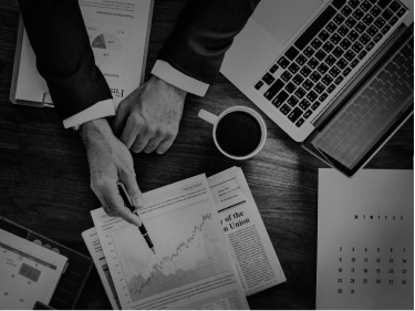Hands reviewing tax documents and financial charts beside a laptop and coffee