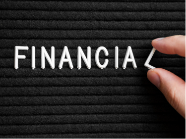 Close-up of hands arranging letters spelling FINANCIAL on a letter board